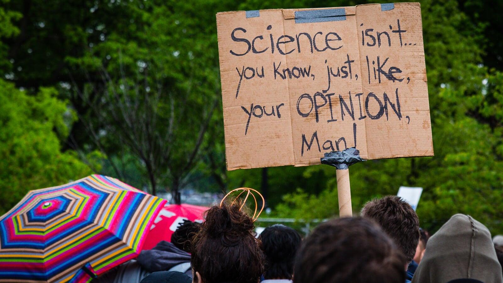 Cardboard-and-duct tape sign reading "Science, isn't ... you know, just, like, your OPINION, Man!"